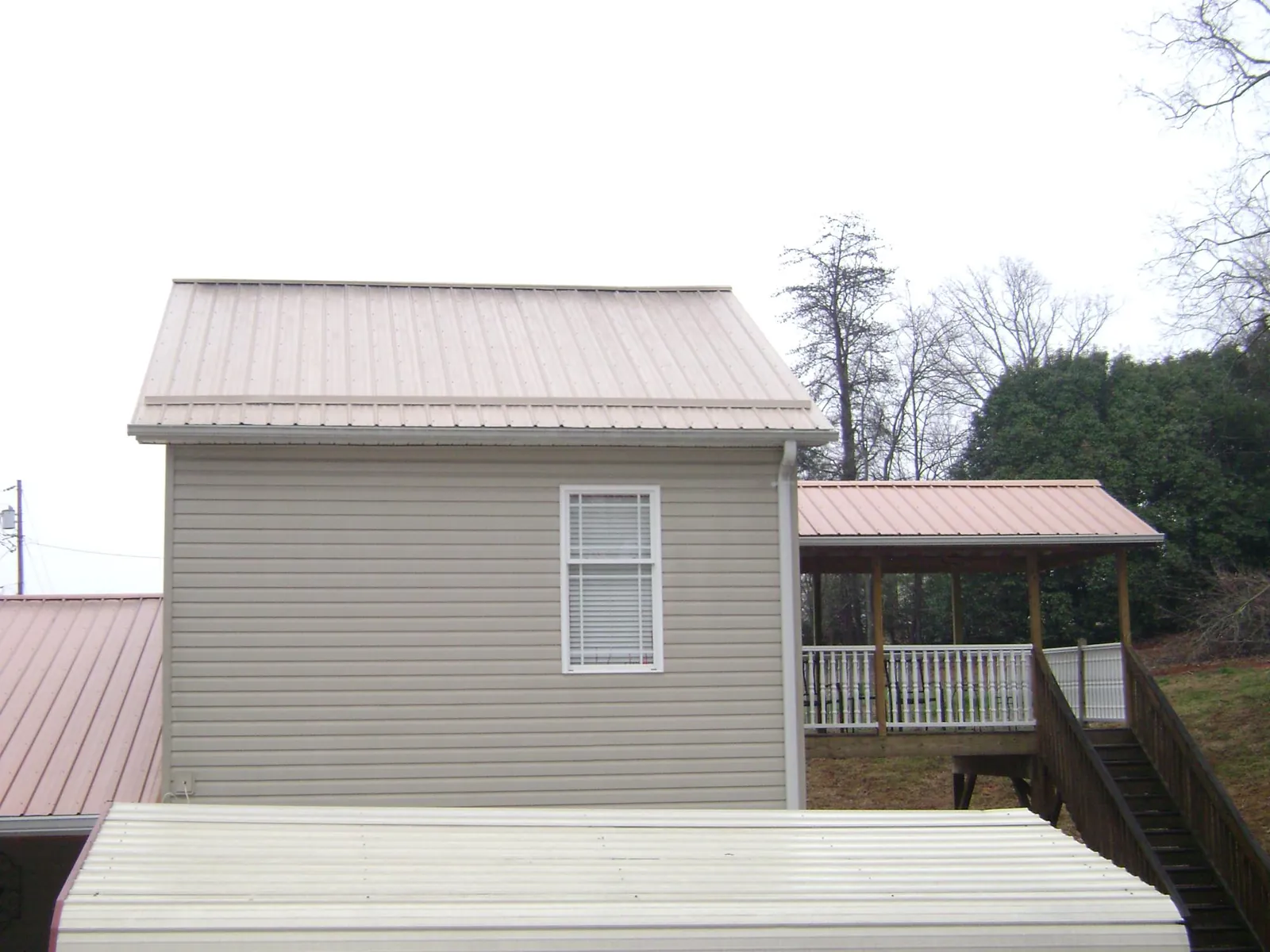Tan metal roofs on a two story addition and attached porch, from a Roof Replacement job in Everglades City