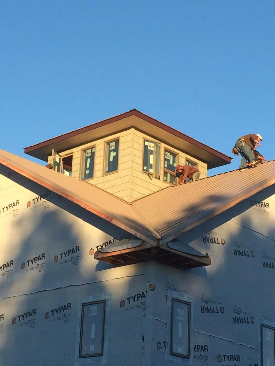 Roofers working around a rooftop cupola on a new metal roof at sunset — Roof Waterproofing in Everglades City by Roofing Brothers